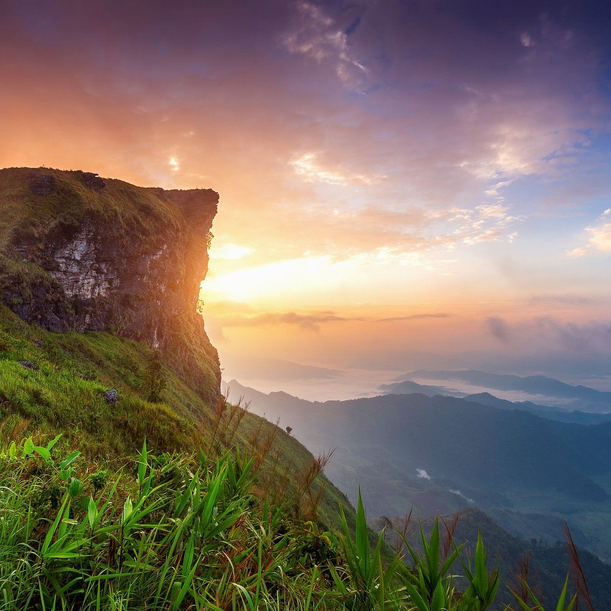 Breathtaking view of a mountain cliff at sunrise with vibrant skies.