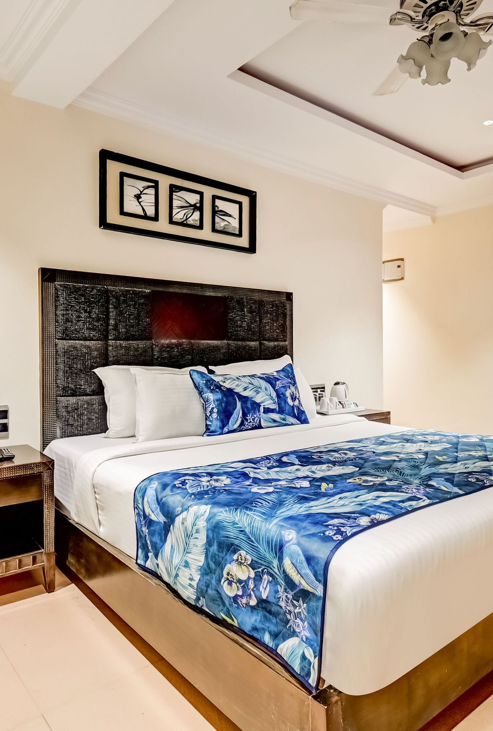 Deluxe room with a private balcony featuring a large bed, flanked by wooden bedside tables, and a photo frame mounted above the headboard