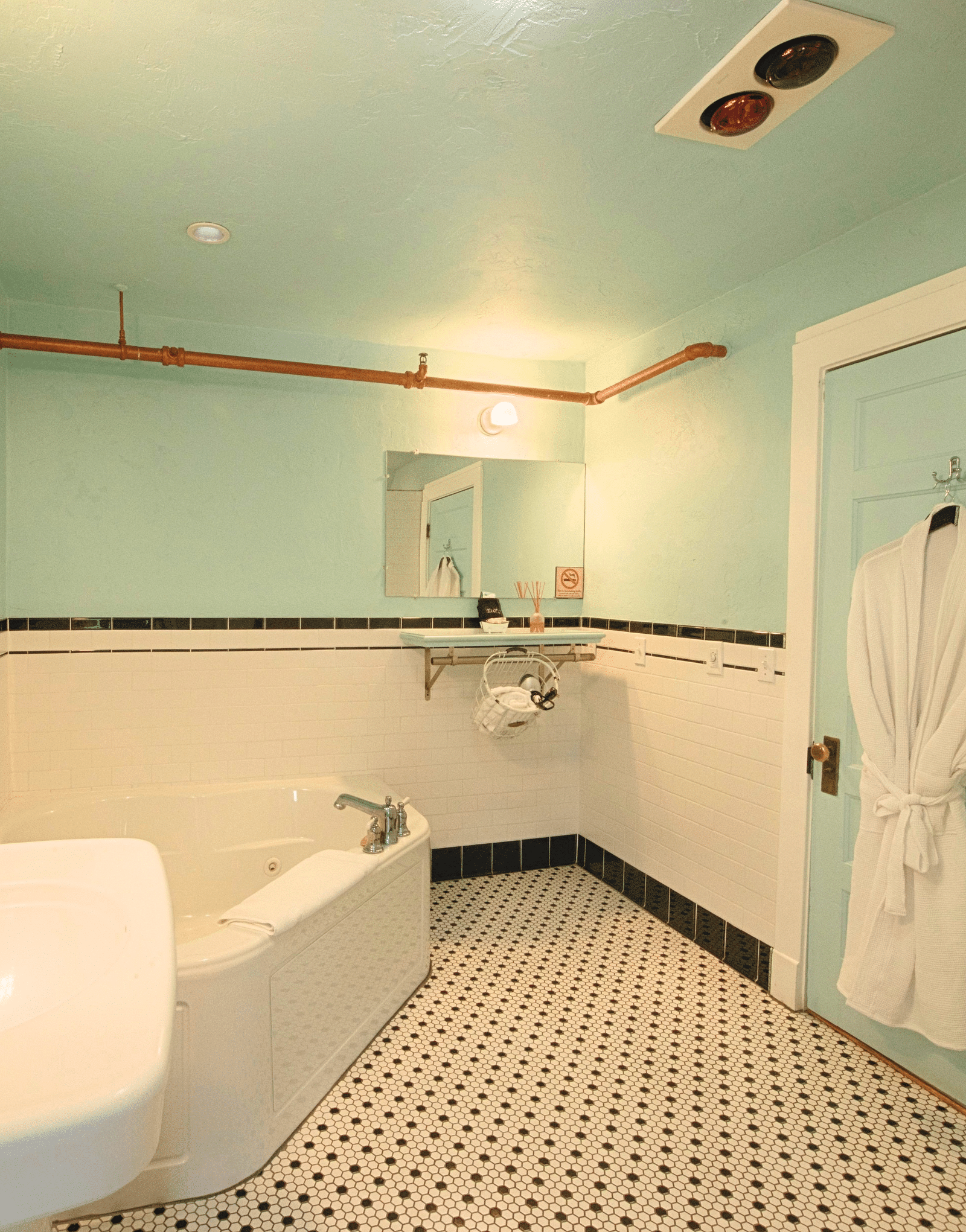 full view image of the bathroom with a wash basin along with a bathtub and a bathrobe hanging behind the door of the bathroom - Historic Tapoco Lodge