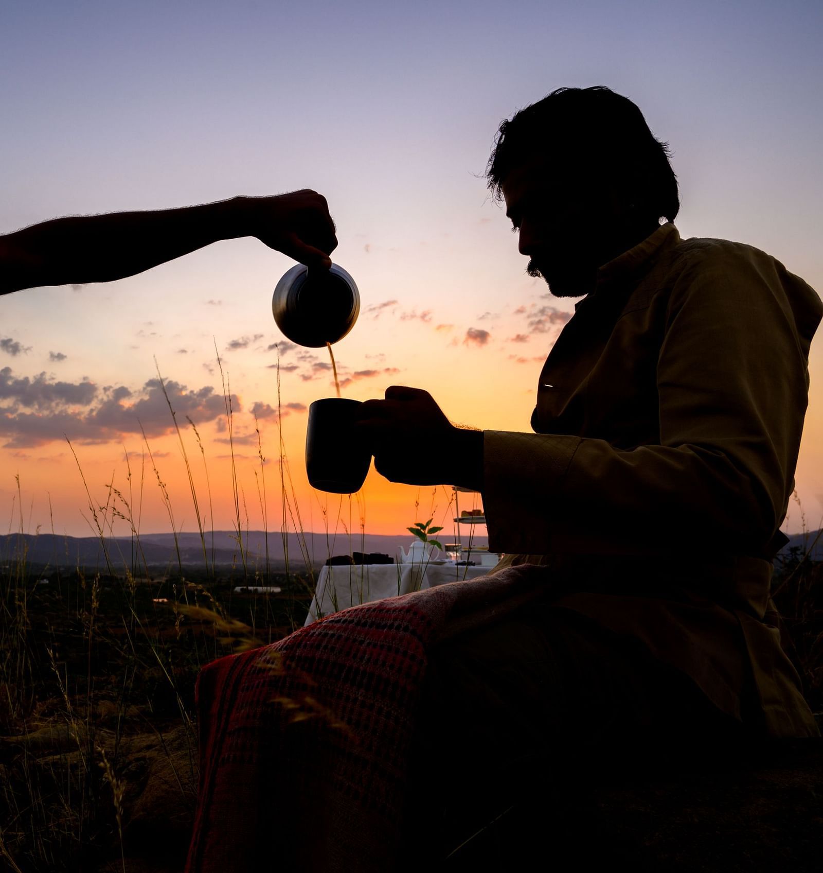 An image of a two men where one is pouring tea for the other in a cup - Utsav Camp Sariska