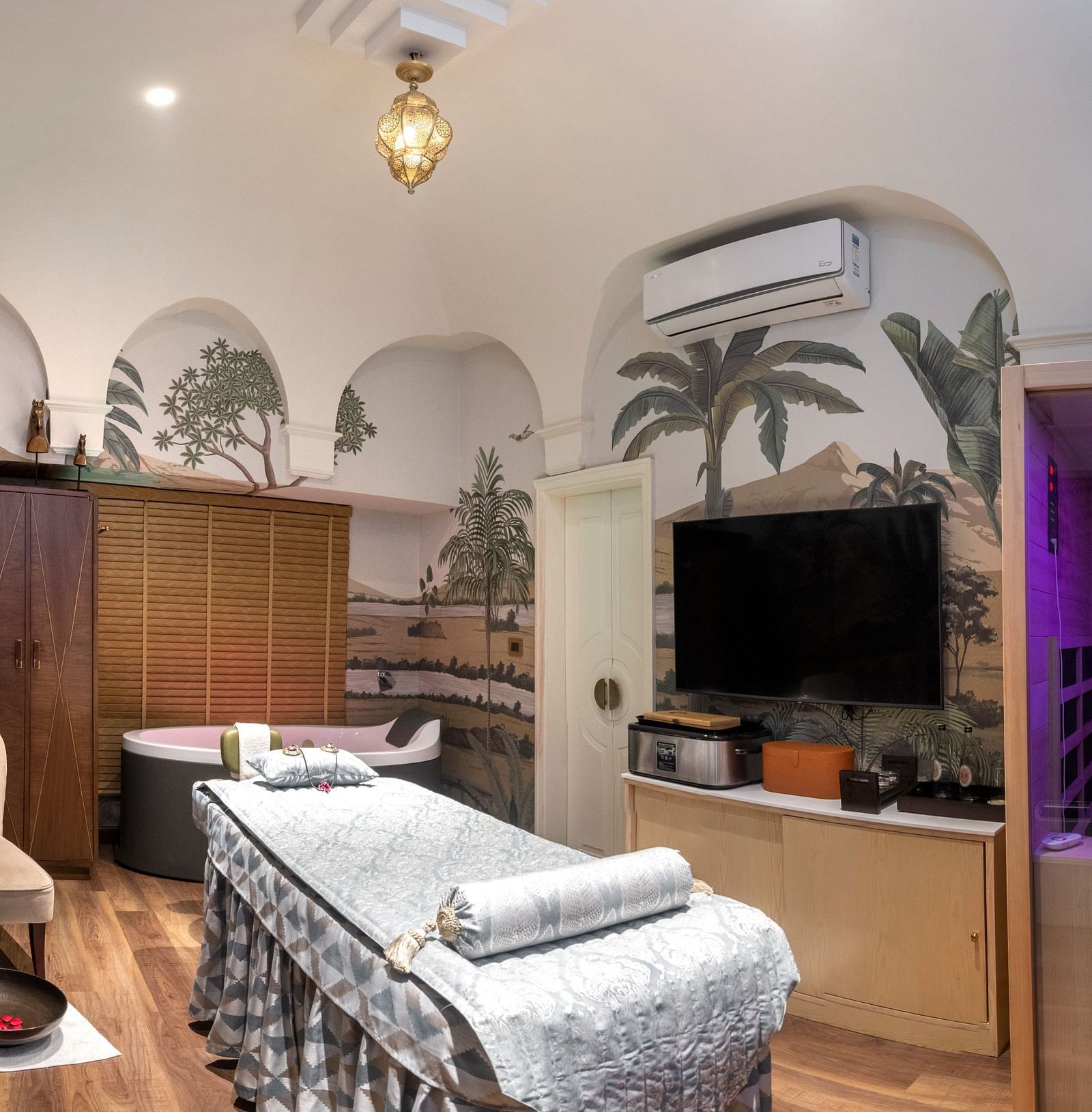 Image of a spa with bed and tropical themed walls at The Claridges New Delhi