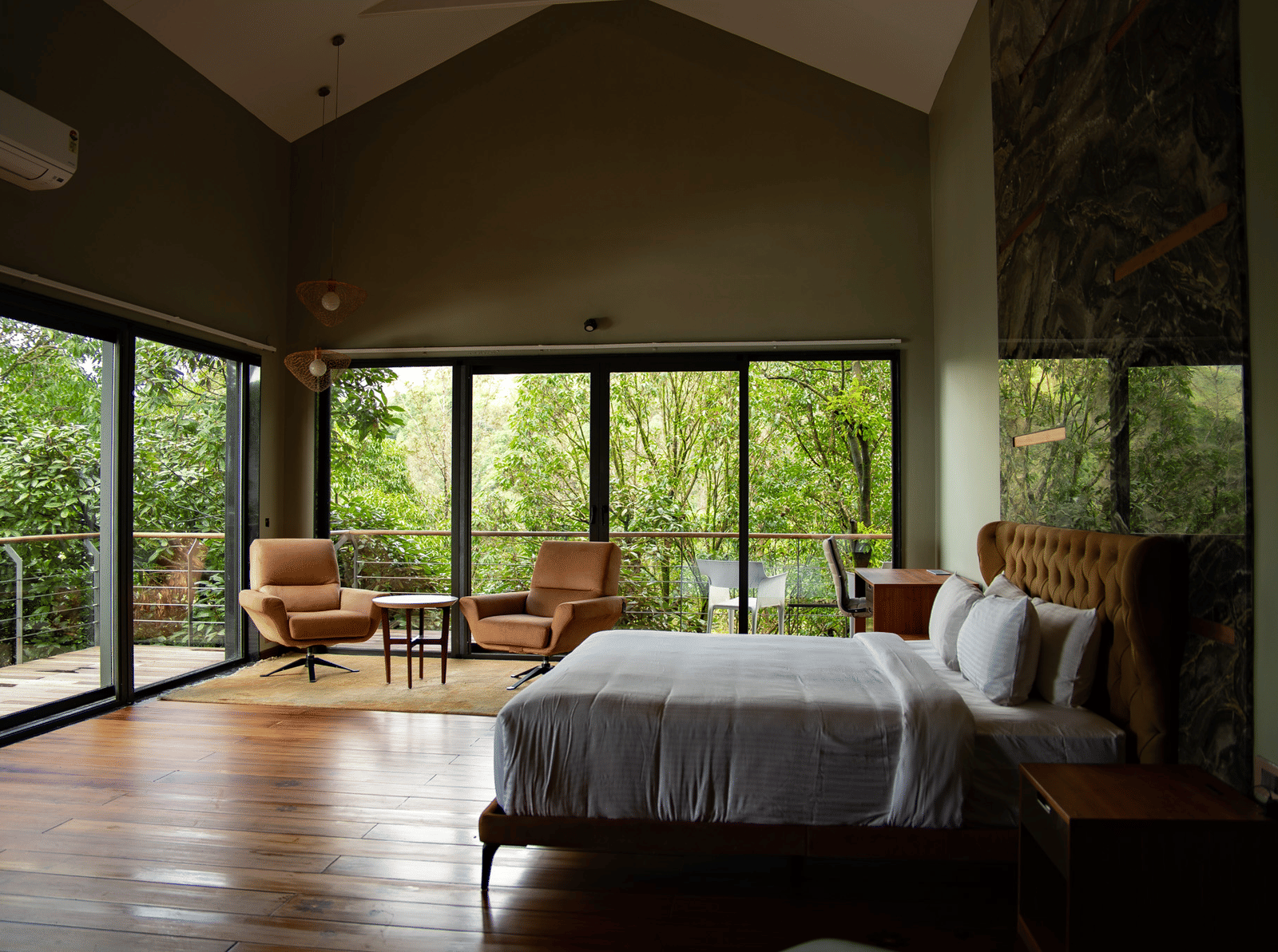 A spacious bedroom at Stanley Revelation with a vaulted ceiling, floor-to-ceiling windows, and a balcony.