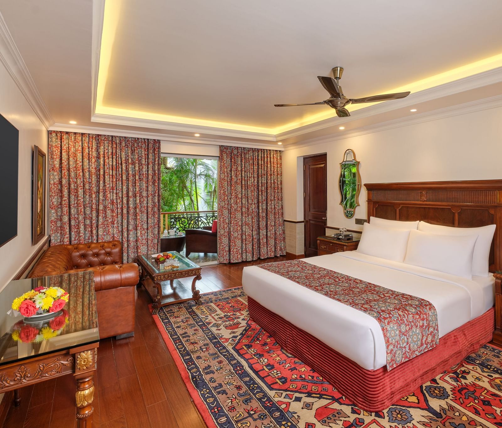 Premium Cottage featuring a wooden bed with white bedding, a decorative rug, a ceiling fan, framed pictures, and a window with bamboo trees, complemented by a patterned curtain