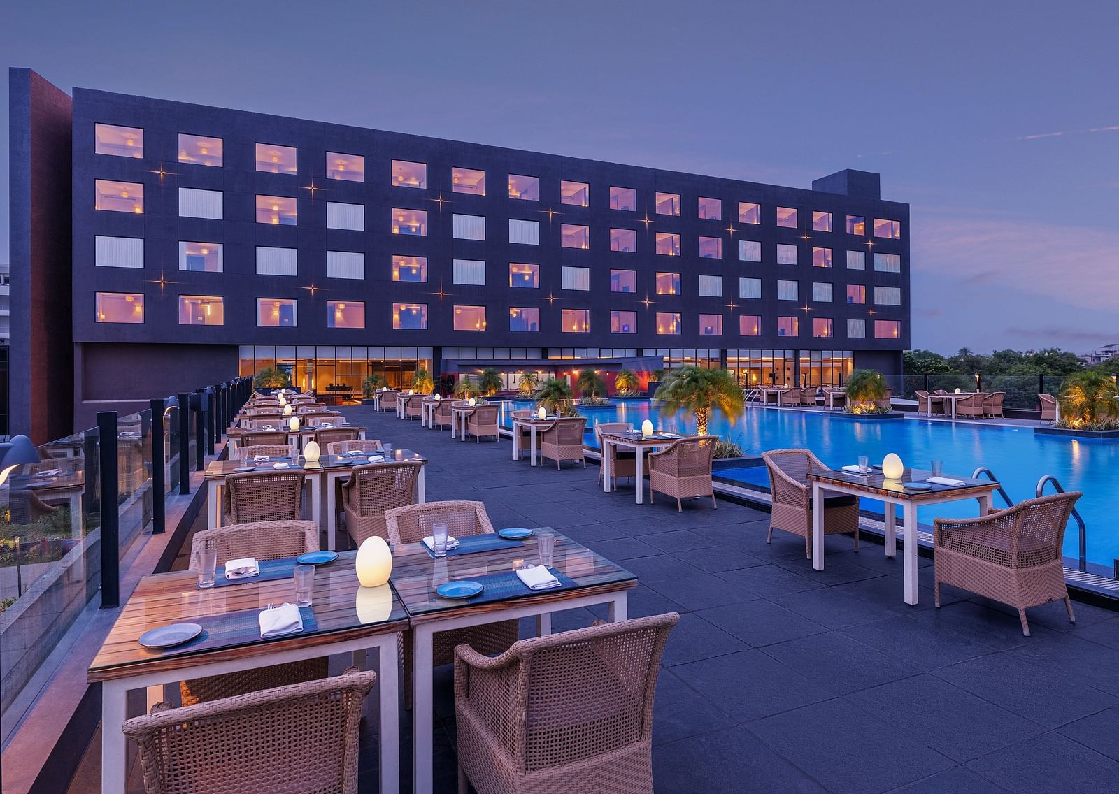 Poolside seating arrangement with the Essentia Luxury Hotel, Indore building in the backdrop