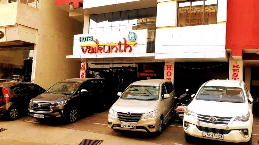 Daytime front view of the hotel building facade with several cars parked in the driveway.