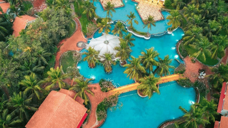 A vibrant aerial view of Radisson Blu Resort Temple Bay with palm trees, large pools and red roof cottages highlighting the Elevate at Temple Bay meeting offer.