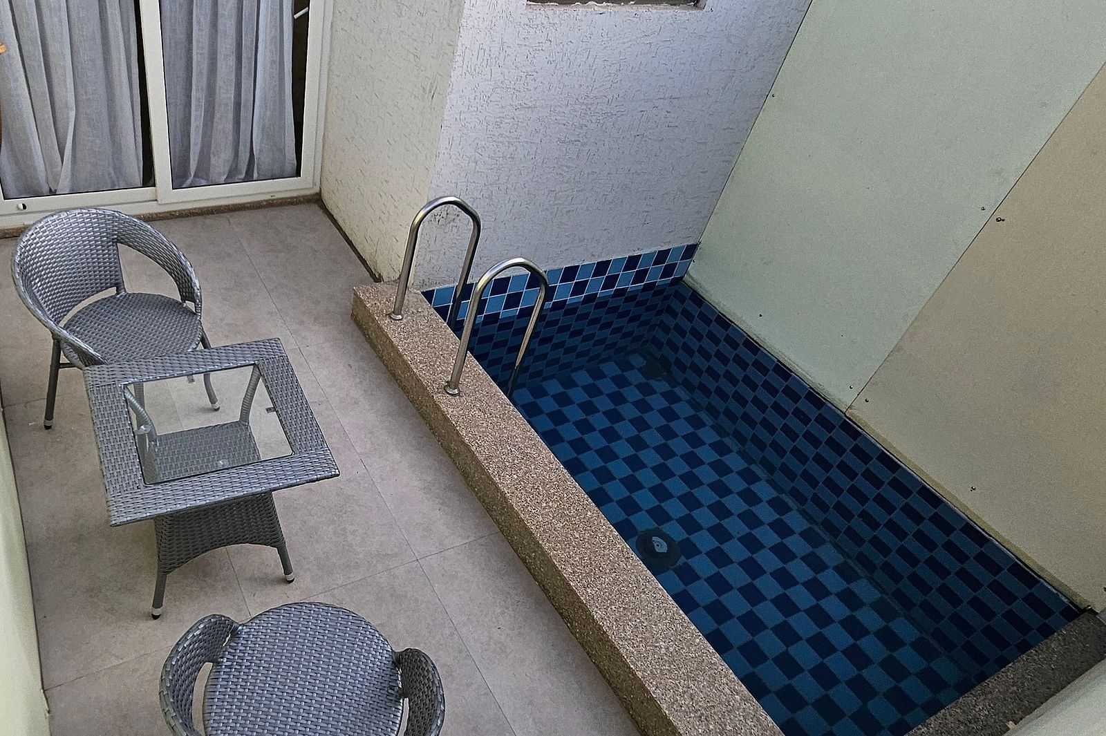 A close-up of a small, outdoor seating area with a pool, two chairs, a coffee table, and a wall mounted decorative lantern - Bamboo Saa Mulberry Resort, Pushkar
