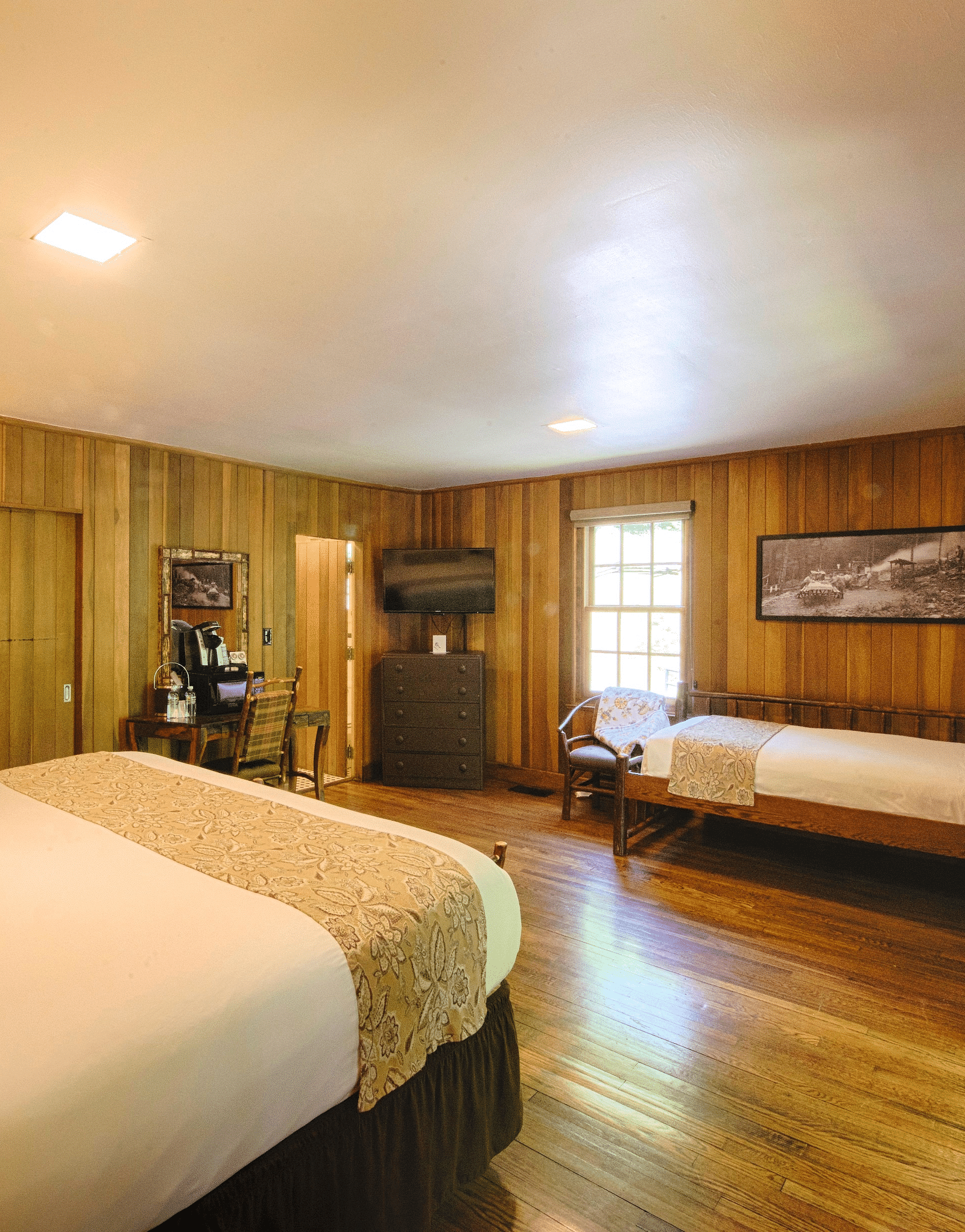 corner view image of a room wooden walls and flooring featuring two plush comfortable beds - Historic Tapoco Lodge