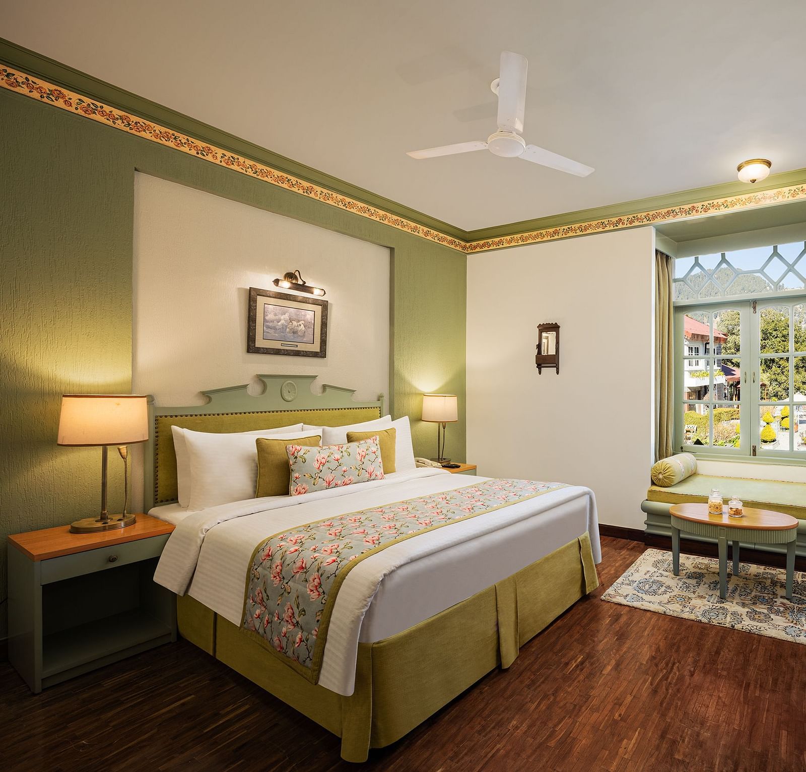 An image of a  cozy room in the naini retreat, nainital, with a king-size bed, wooden furniture, and a window. The room also features a ceiling fan, a TV and wooden flooring.