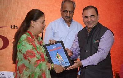 A man presenting a book to a woman in front of a conference backdrop