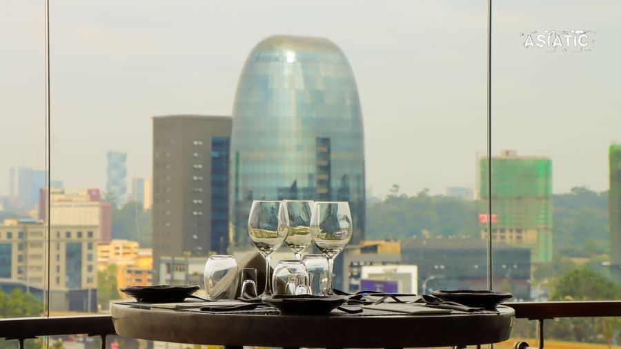 A close view of the table with glass dome covers over food trays set on an outdoor terrace, with a city skyline in the background at Asiatic Lounge.