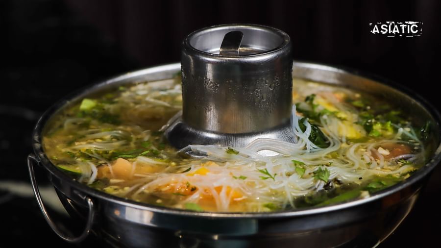 A close view of a metal pot with vegetables and broth cooking at Asiatic Lounge.