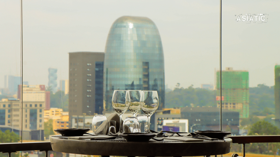 A close view of the table with glass dome covers over food trays set on an outdoor terrace, with a city skyline in the background at Asiatic Rooftop Bar and Restaurant.