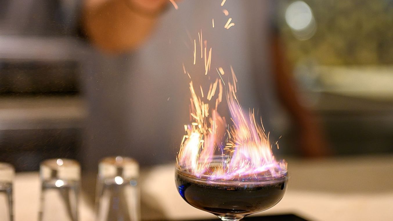 A bartender sprinkling salt on a fiery drink; the bartender seen in the backdrop - Maikhao Dream Villa Resort & Spa, Phuket
