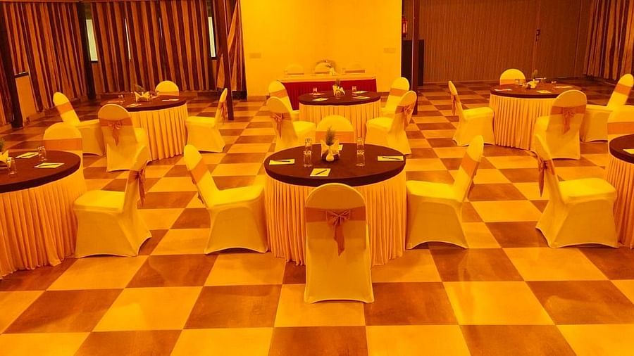 An indoor venue featuring round tables and chairs with warm lighting | Ballroom | Woodstock Resorts, Coorg