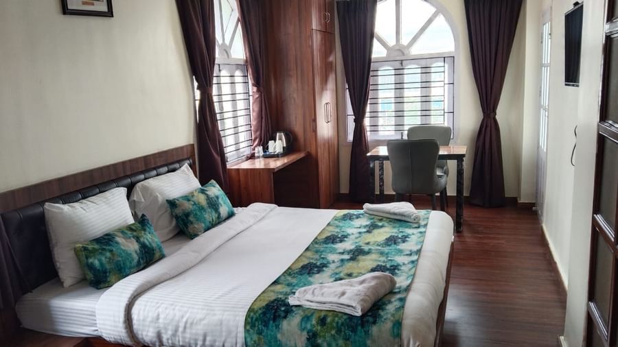 A double bed with towels kept on them inside Premium room with balcony 