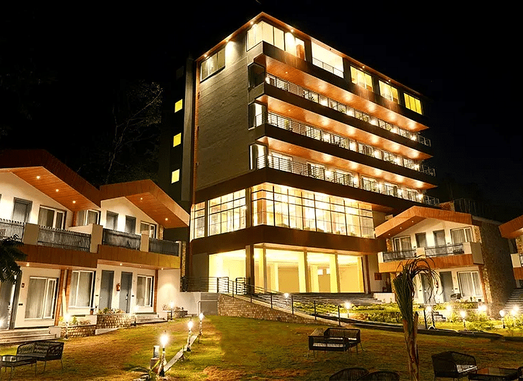 a facade image of a hotel premises featuring a vast lawn in the foreground