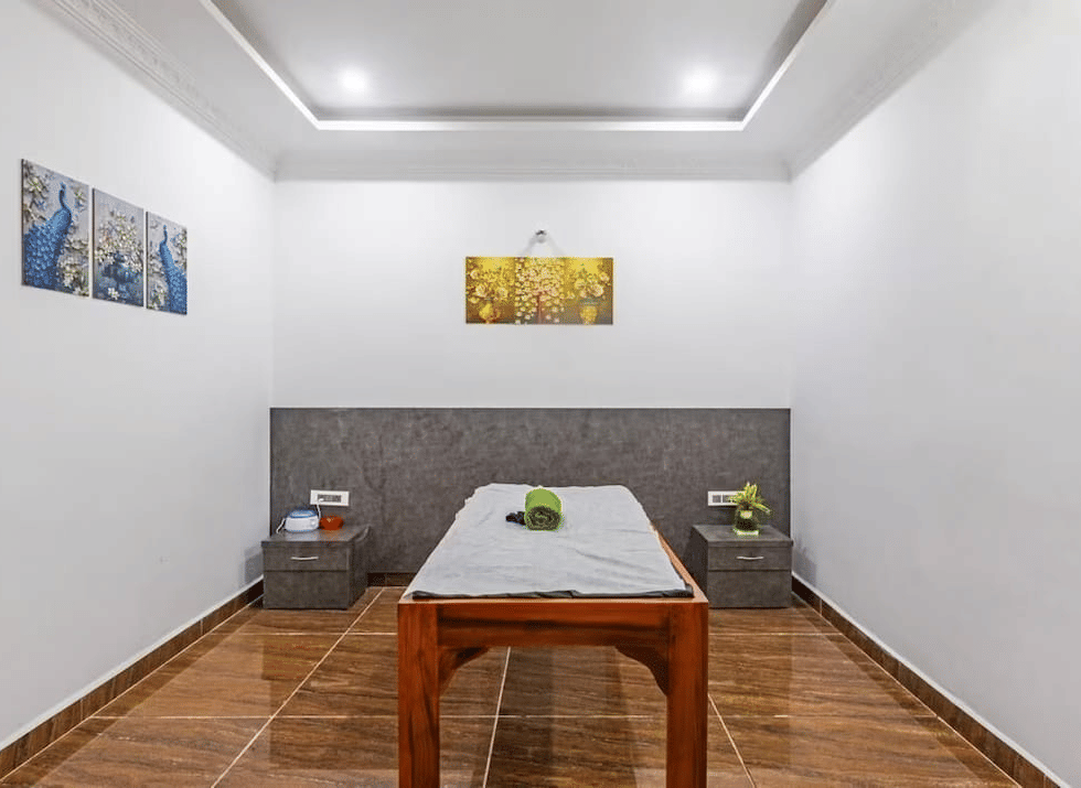 Minimalist spa room with a wooden table and decorative wall art at Siri Ambari Resorts and Spa.
