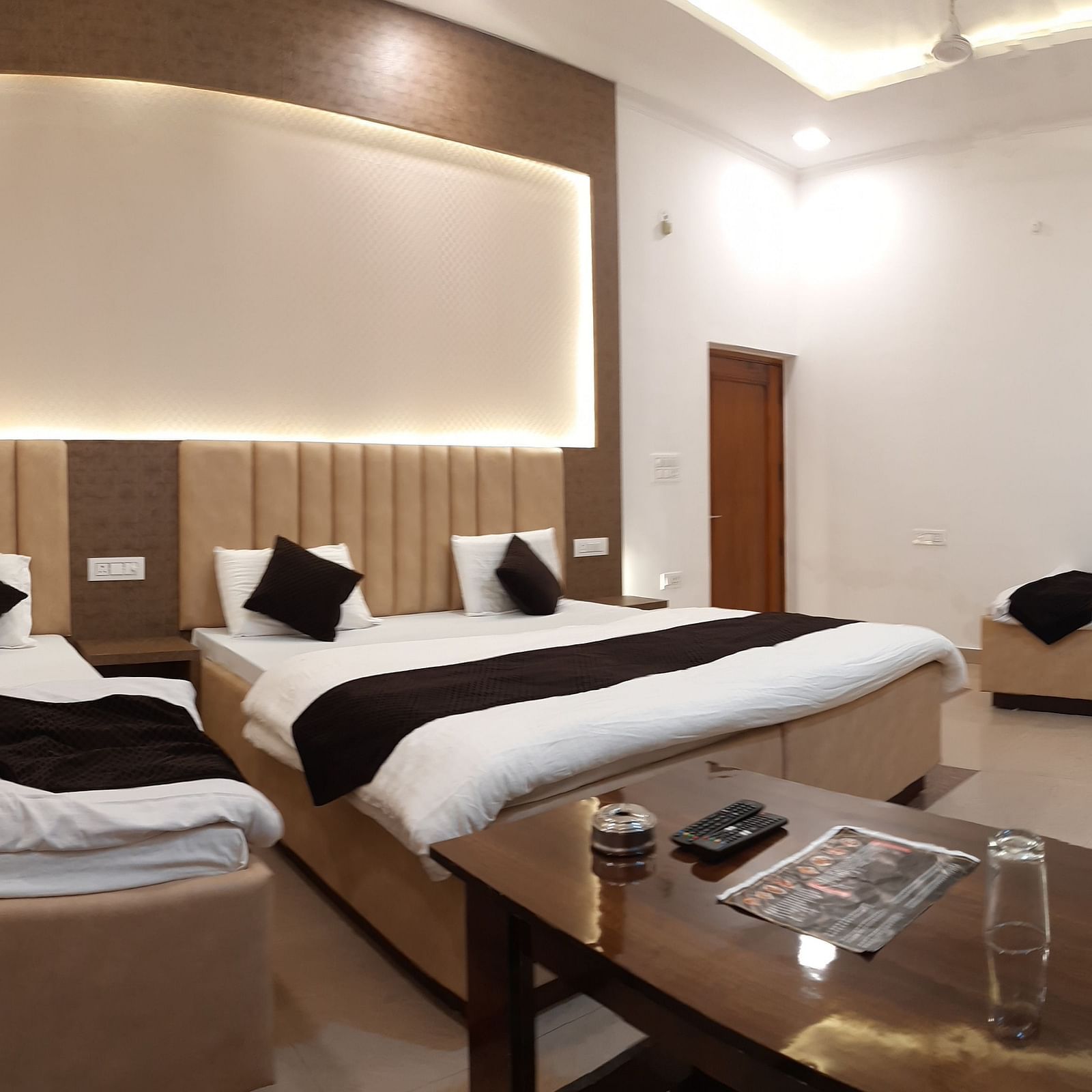 A hotel room in Roorkee with bright lights, a king size bed, two single beds and a teapoy - Motel Divine International, Roorkee