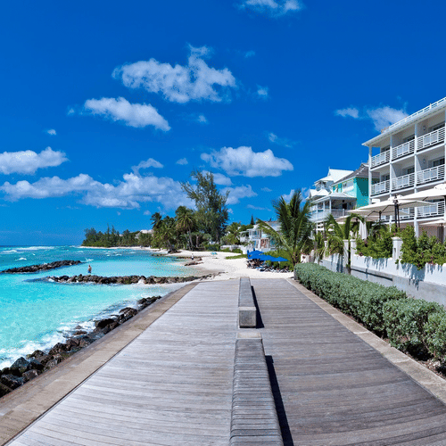 Oceanfront pathway beside The Soco Hotels with clear turquoise water seen during a bright sunny sky.