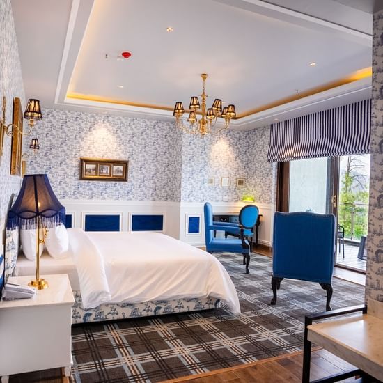 A hotel room with a large bed and comfy blue chairs  - The Manor Luxury Hotel, Shimla