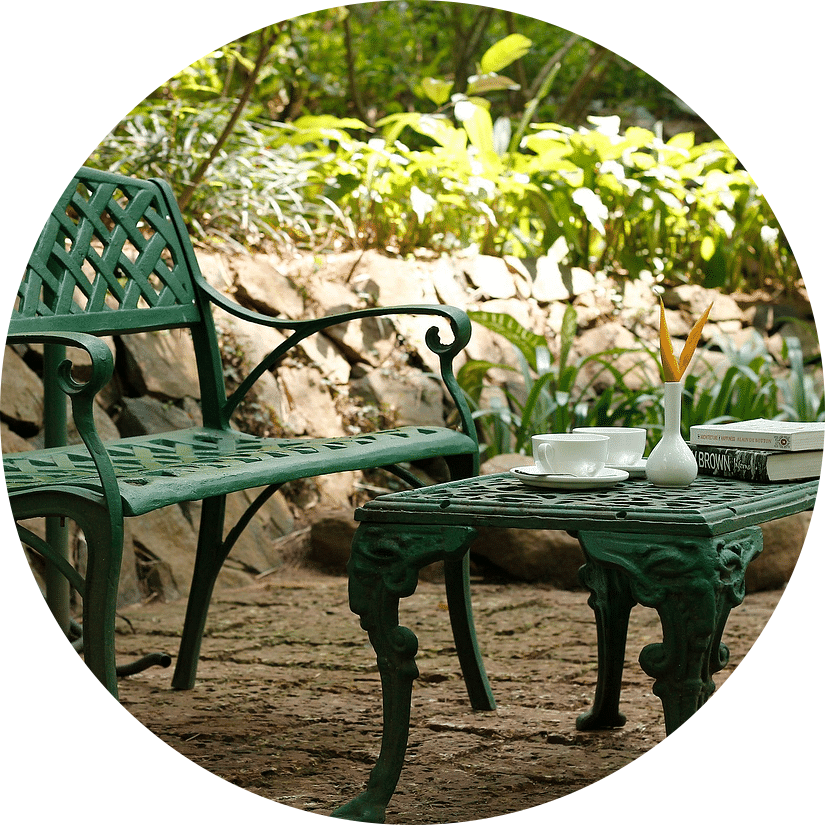 A green metal garden chair and table with a book-Amanvana Spa Resort, Coorg - Luxury Resort