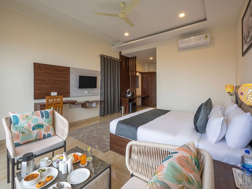 a double bed with chairs next to it inside one of the rooms - Stone Wood Mountain Resort, Dharamshala