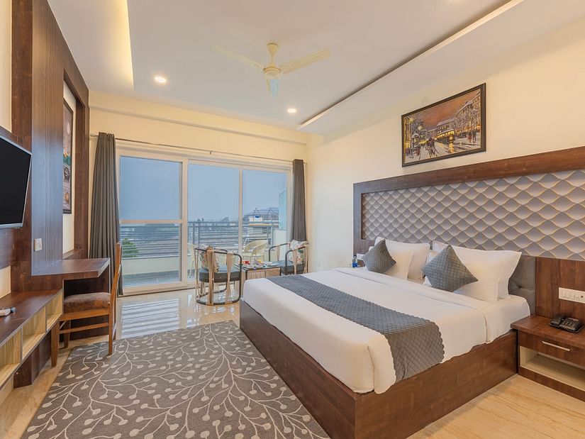 a double bed with a TV opposite it inside one of the rooms - Stone Wood Mountain Resort, Dharamshala - Dharamshala Place to Stay