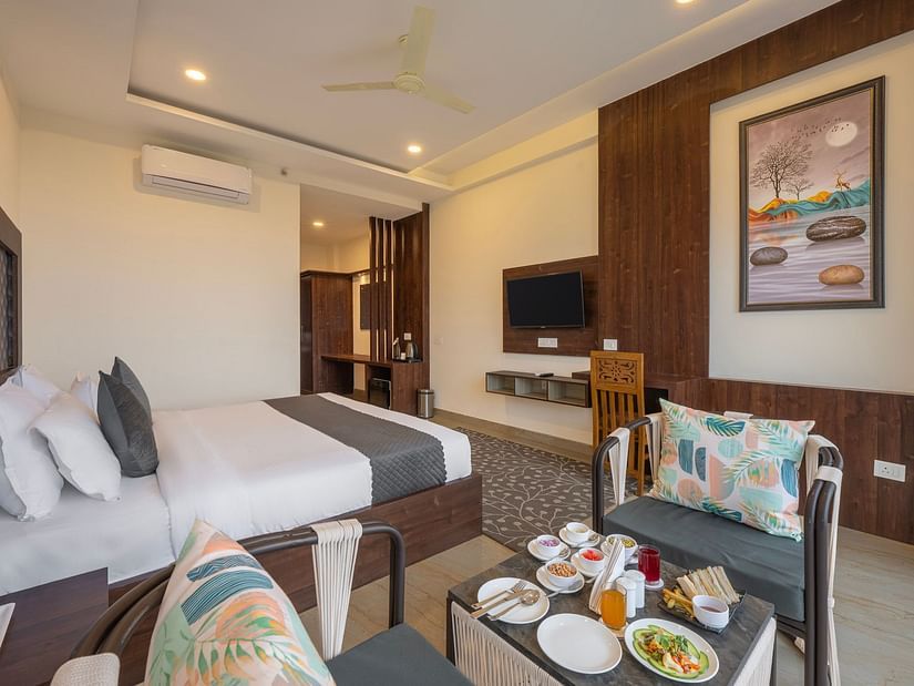 a double bed next to a sofa inside one of the rooms - Stone Wood Mountain Resort, Dharamshala