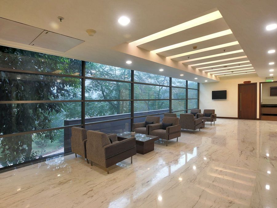 Modern lounge area with comfortable armchairs, large windows overlooking greenery, and a polished floor - Heritage Village Resorts & Spa.