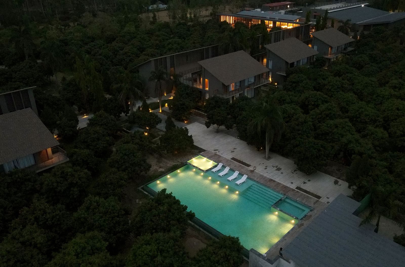 Aerial night view of the illuminated outdoor swimming pool surrounded by lush greenery at Wyndham Garden.