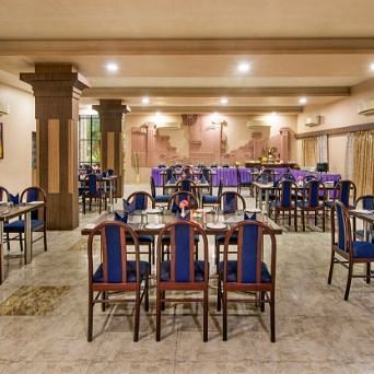 A large dining area is prepared with numerous tables and blue chairs - Lion Lords Inn Rajula