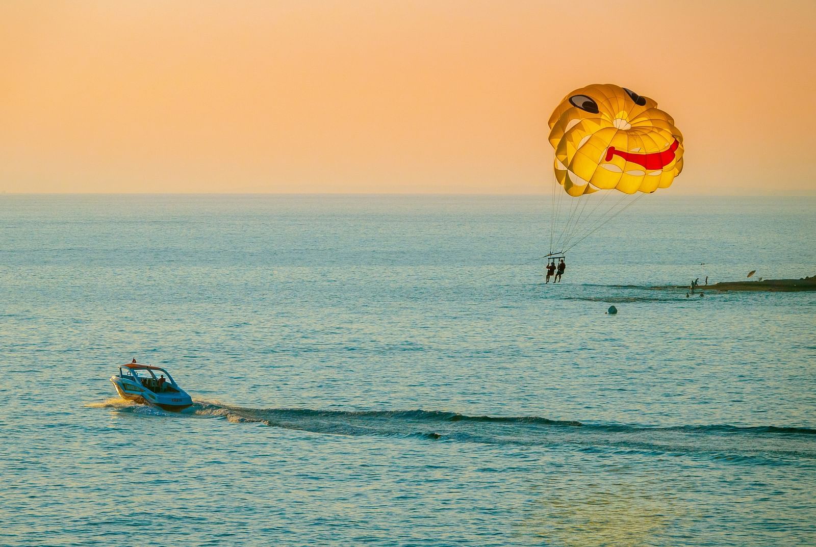 A group of people parasail from a boat over the ocean.