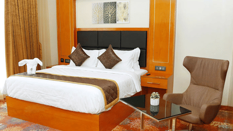 A double bed along side an elegant modern armchair with a coffee table in front of it at the Suite of Leroy Grand, Yeshwathpur.