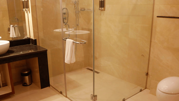 The bathroom at the Executive room featuring a glass-enclosed shower cubicle besides the vanity area at Leroy Grand, Yeshwanthpur.