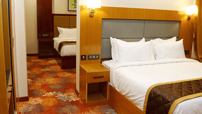 Side view of the Family Suite showcasing the 2 bedrooms, each with a double bed and carpeted flooring at Leroy Grand, Yeshwanthpur.