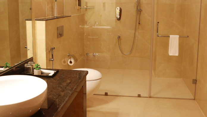 The bathroom at the Suite featuring a shower cubicle separated by glass partitions at Leroy Grand, Yeshwanthpur.