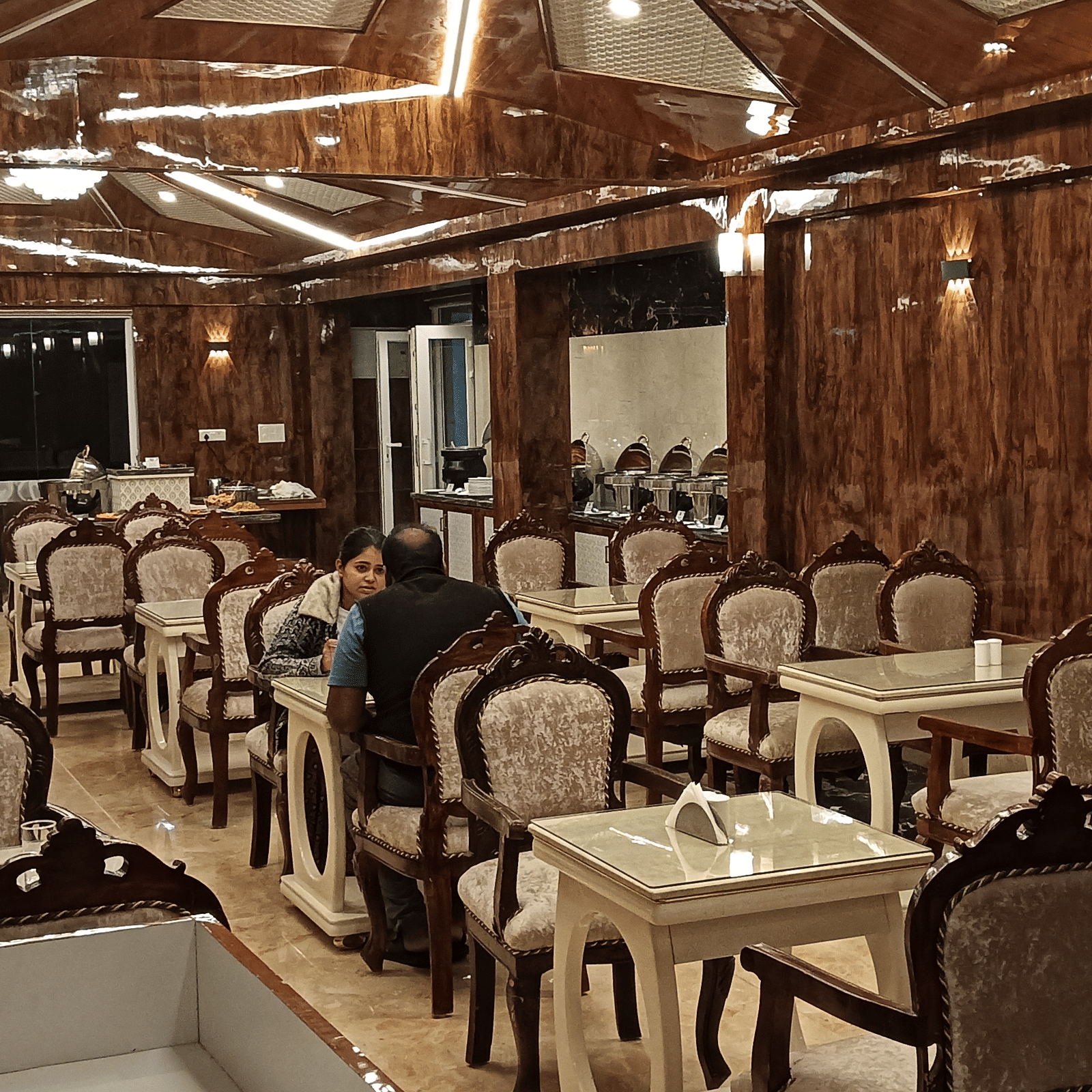 A well-lit multi-cuisine restaurant with wooden interiors and cosy dining setup for guests - Benzz Park, Kodaikanal