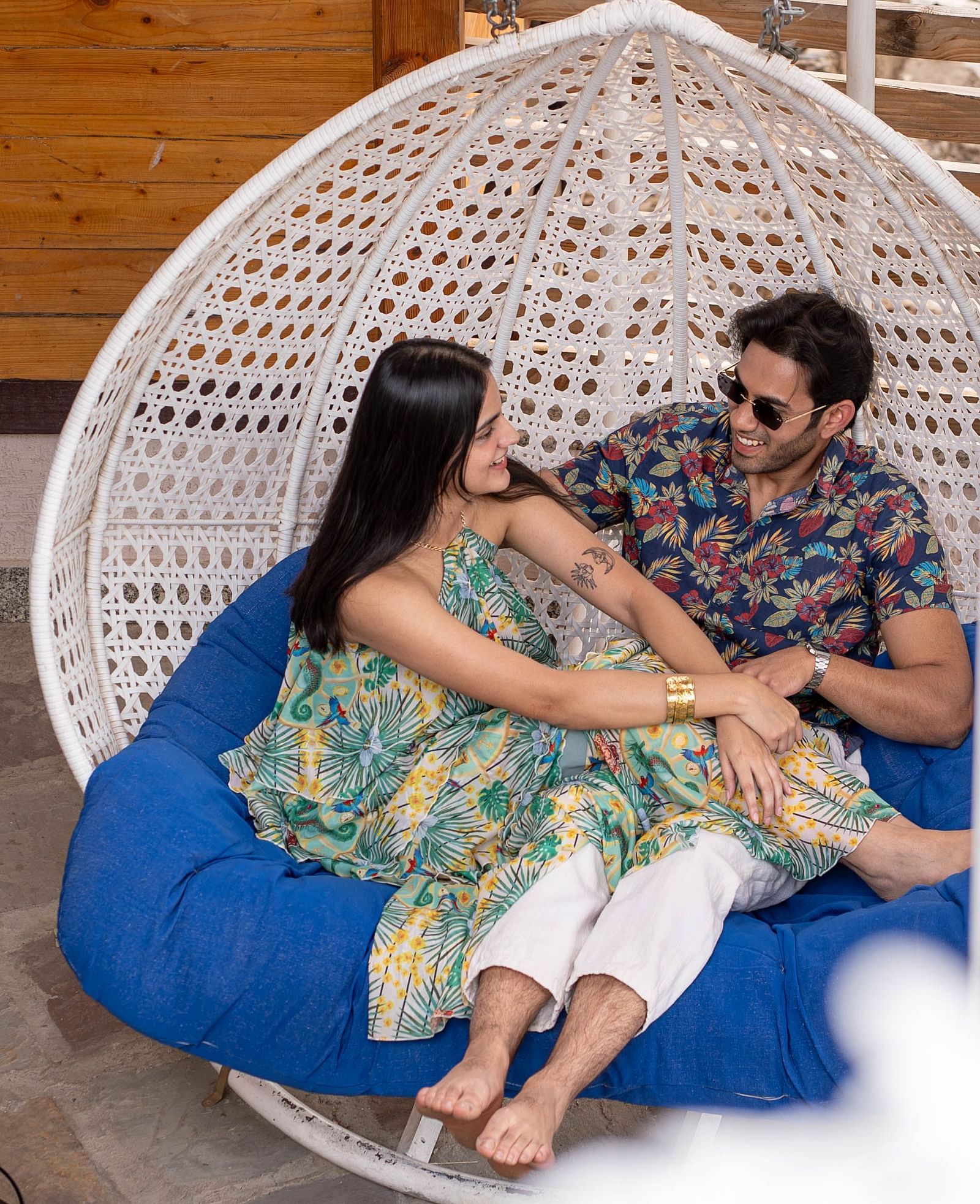 A man and a woman looking at each other and smiling in a swing.