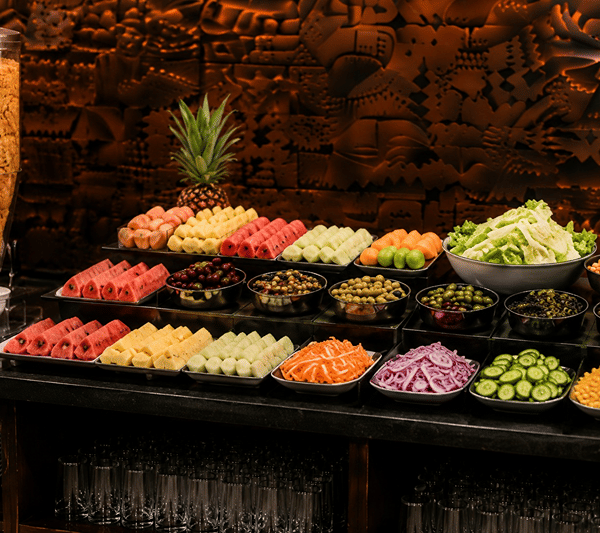 Buffet counter at Lime Tree Hotel & Banquet, Jaipur, with platters of sliced fruit, chopped vegetables and a pineapple.