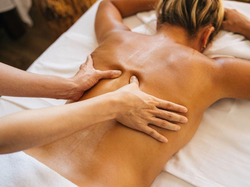 A woman receives a relaxing deep tissue back massage with oil on a spa bed