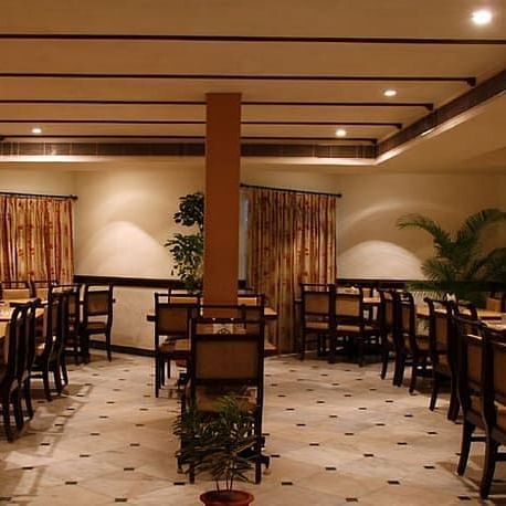Side view of Akshara Restaurant with multiple chairs and modern interior - Jayaram Hotel, Pondicherry