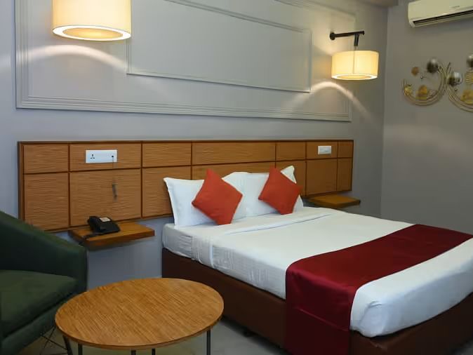 A well-designed hotel room with two beds, modern lighting, and a cosy seating area - Max Hotel Prayagraj.