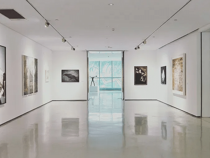 An art gallery with white walls and several framed pictures hanging.