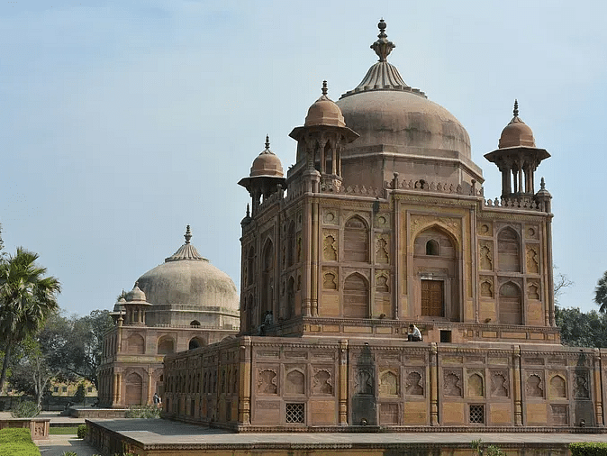A large mausoleum with a white dome and surrounding gardens.