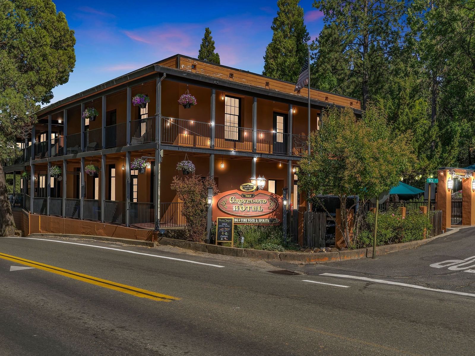 Facade of The Groveland Hotel with trees surrounding the building on a clear, blue day.