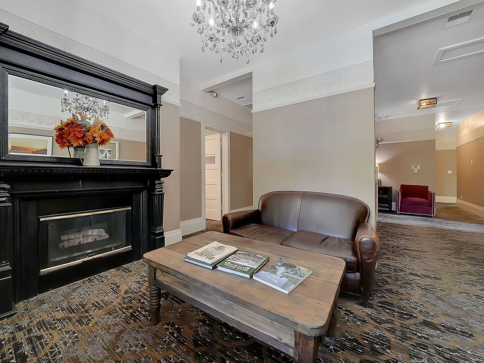 a coffee table and a sofa chair in front of a fireplace - The Groveland Hotel.