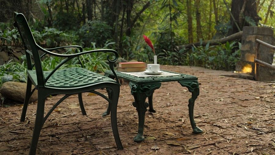 Outdoor garden seating with a green metal chair and table set on a gravel floor