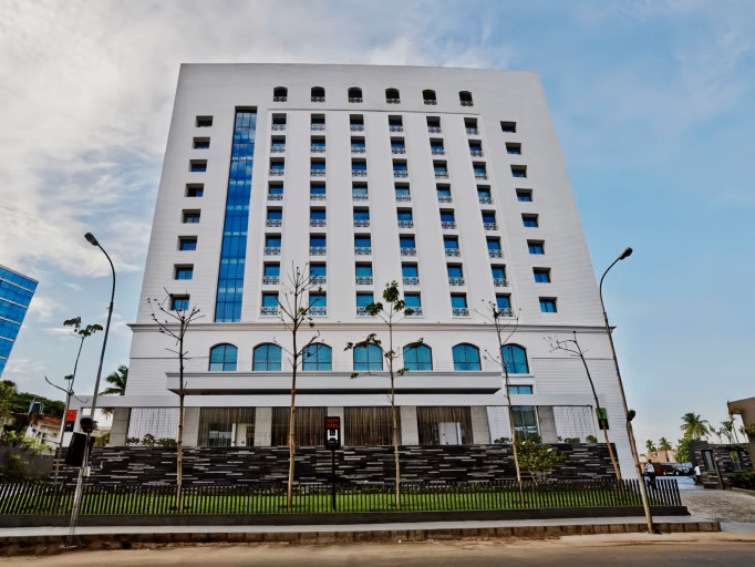Daytime facade view of Hablis Hotel in Chennai with street lights in front of it and blue sky in the background. One of the best Corporate Team Outing Places in Chennai.