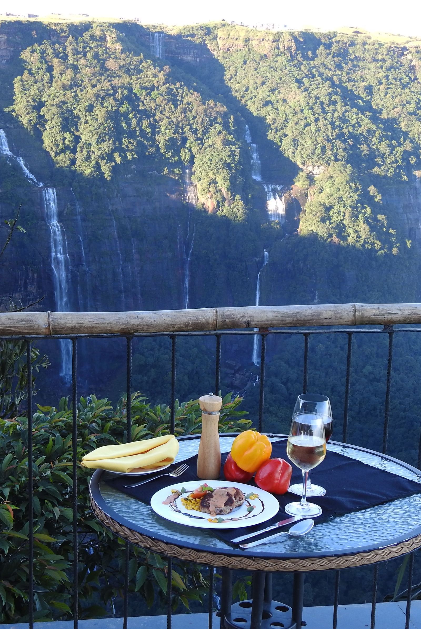 A table in the balcony with food and drinks facing the waterfalls at Polo Resort Cherrapunjee.